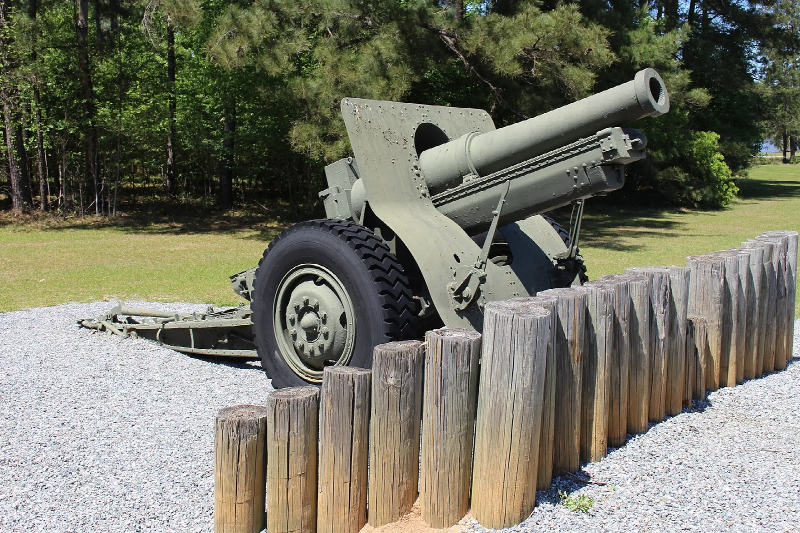 Green howitzer behind a wall of log posts