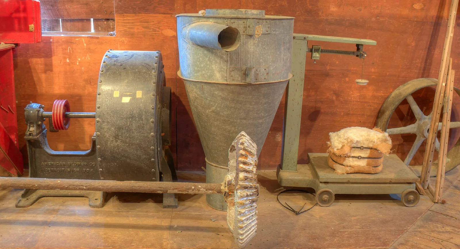 Old milling machinery against a red wooden wall