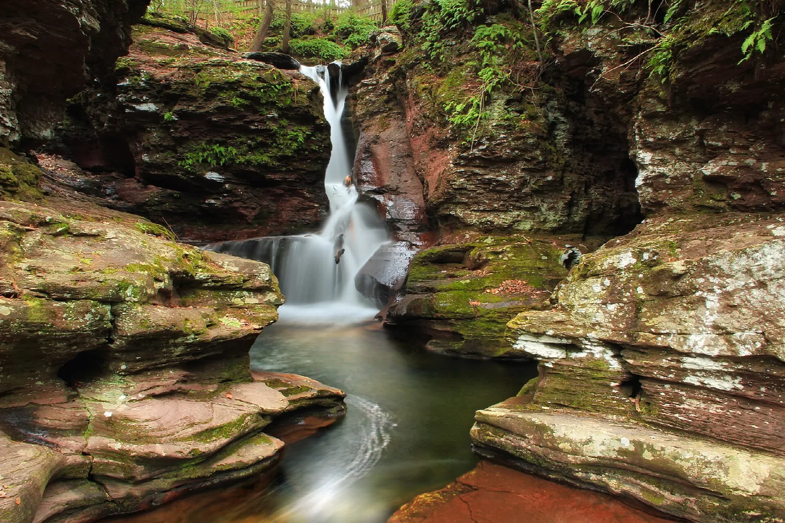 Narrow waterfall dropping into a pool between mossy rock walls