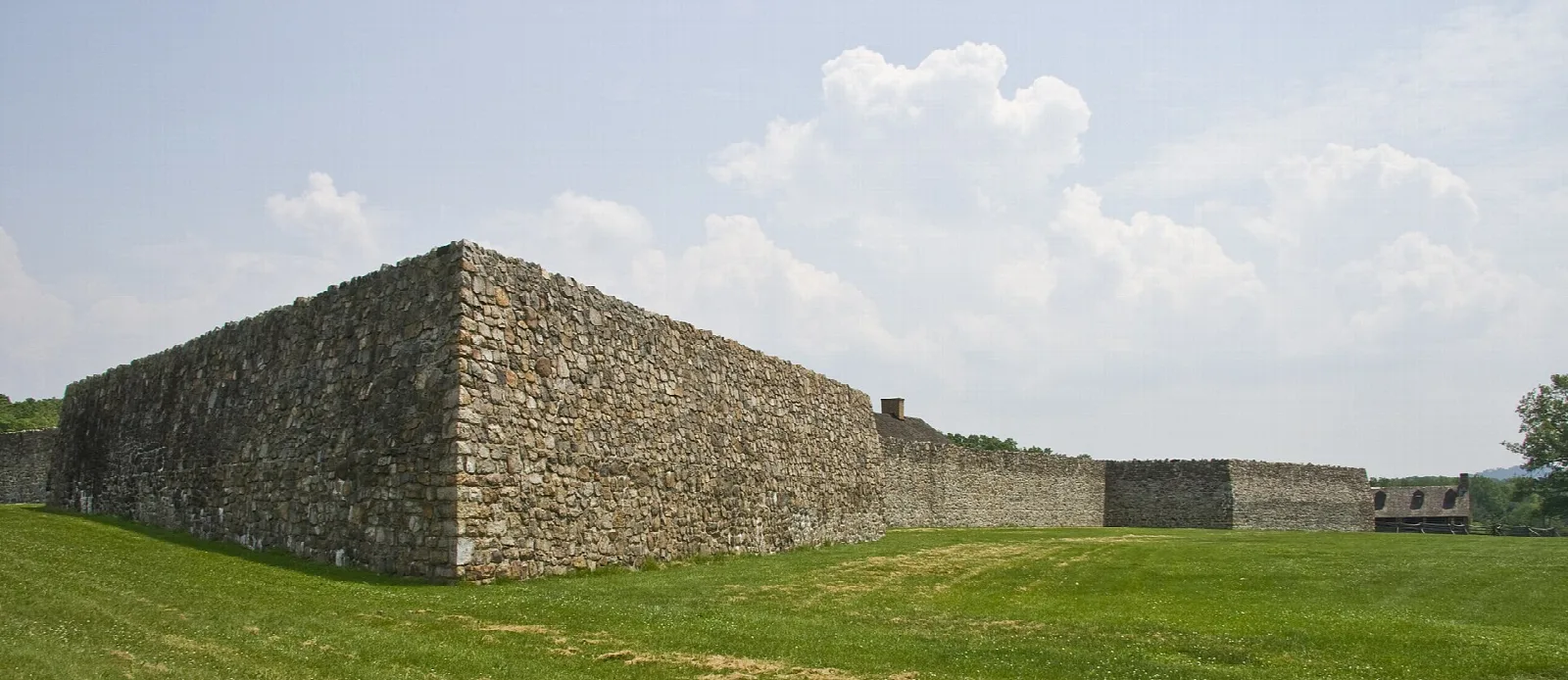 Long stone fort wall rising above a green lawn