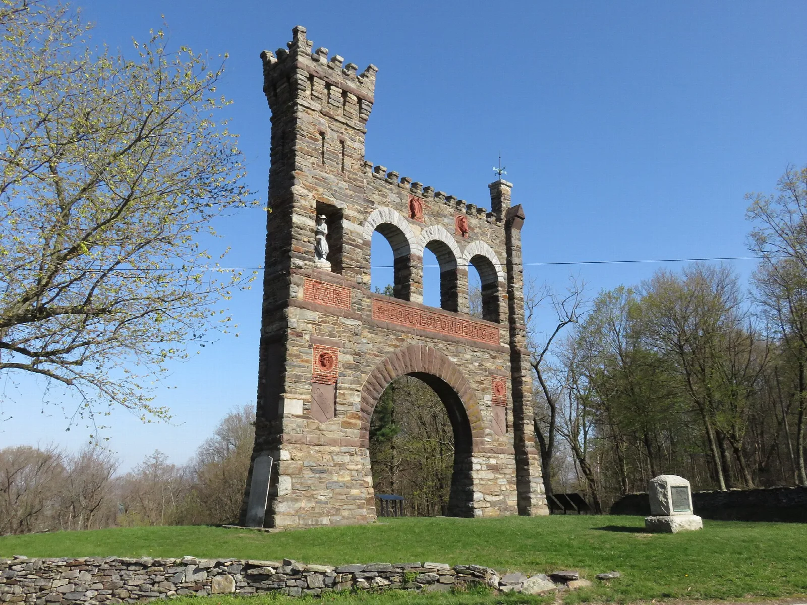 Tall stone memorial arch with towers under a blue sky