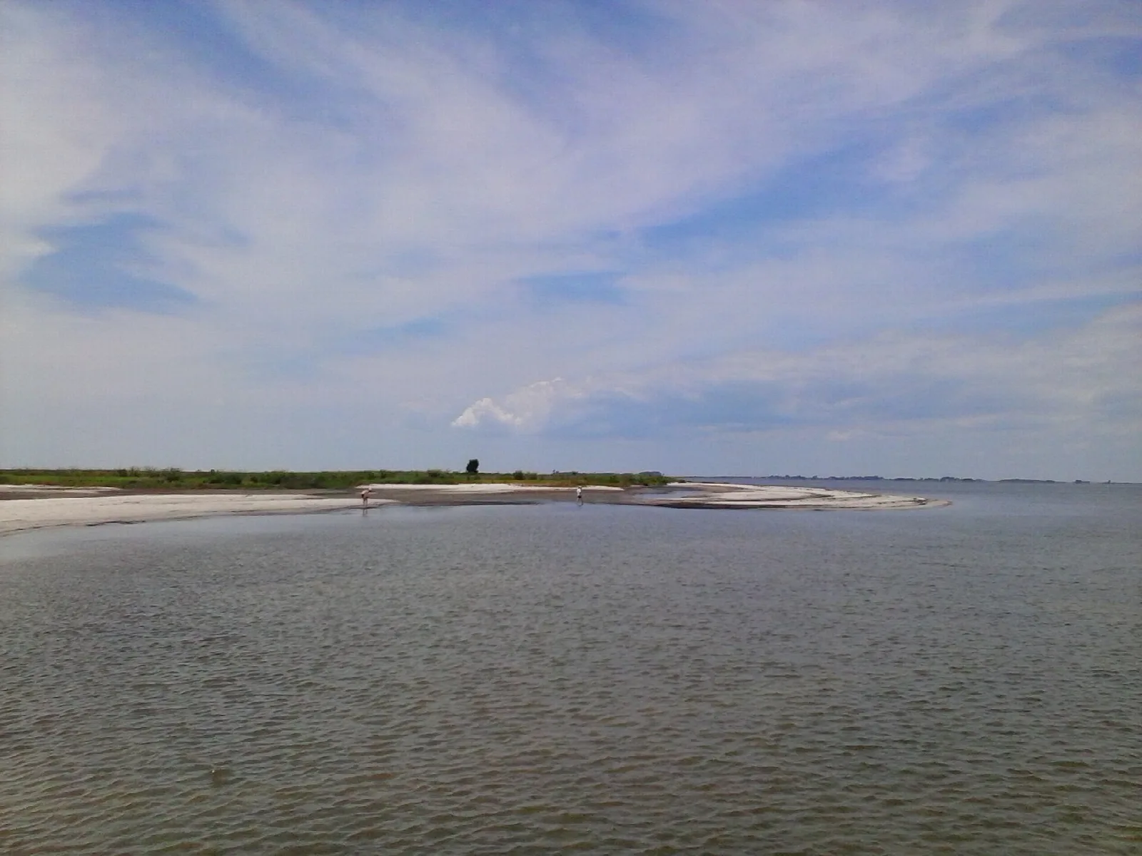 Sandy bar at the edge of calm Chesapeake Bay water under blue sky
