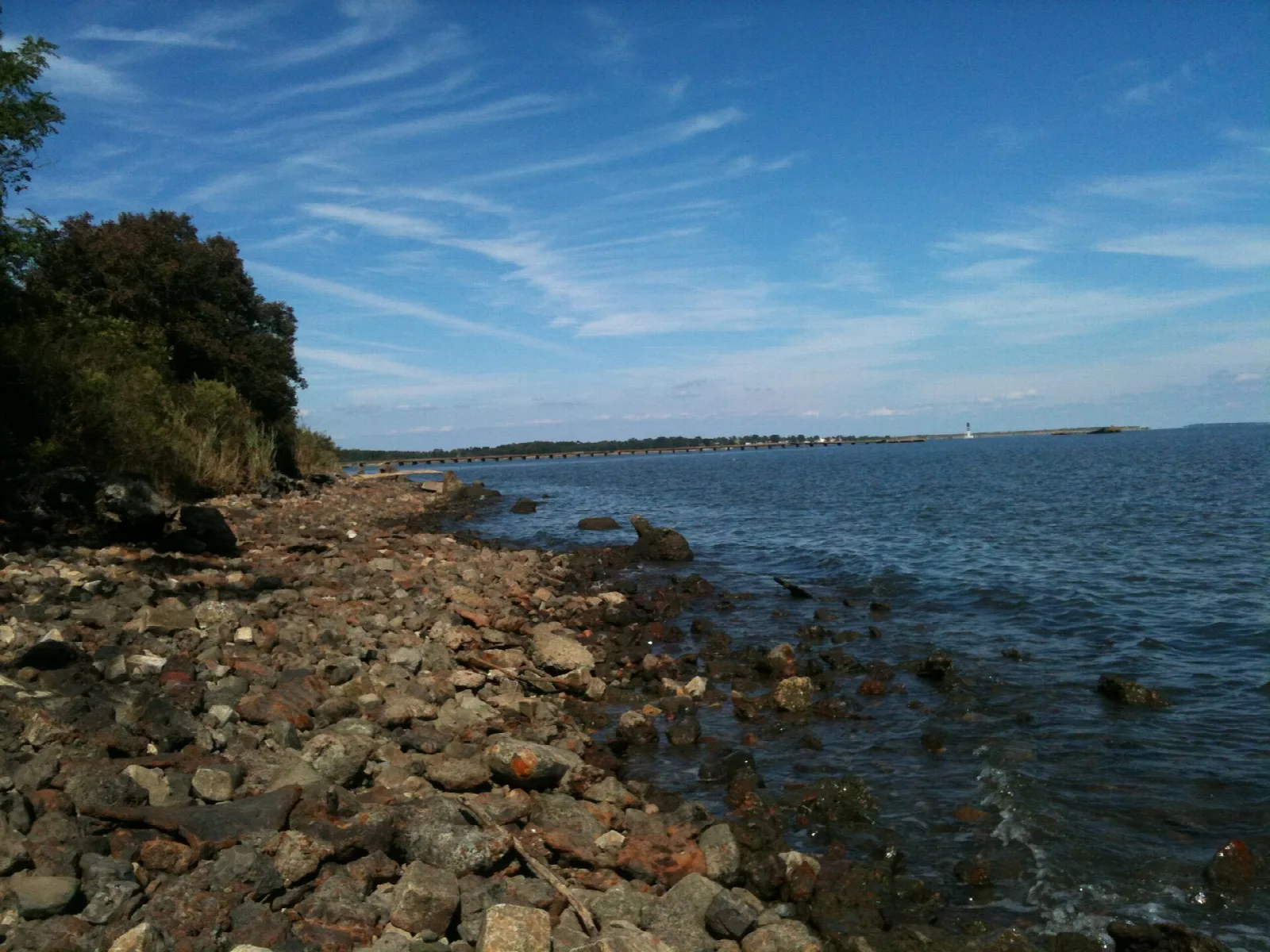 Rocky shoreline beside open blue bay water