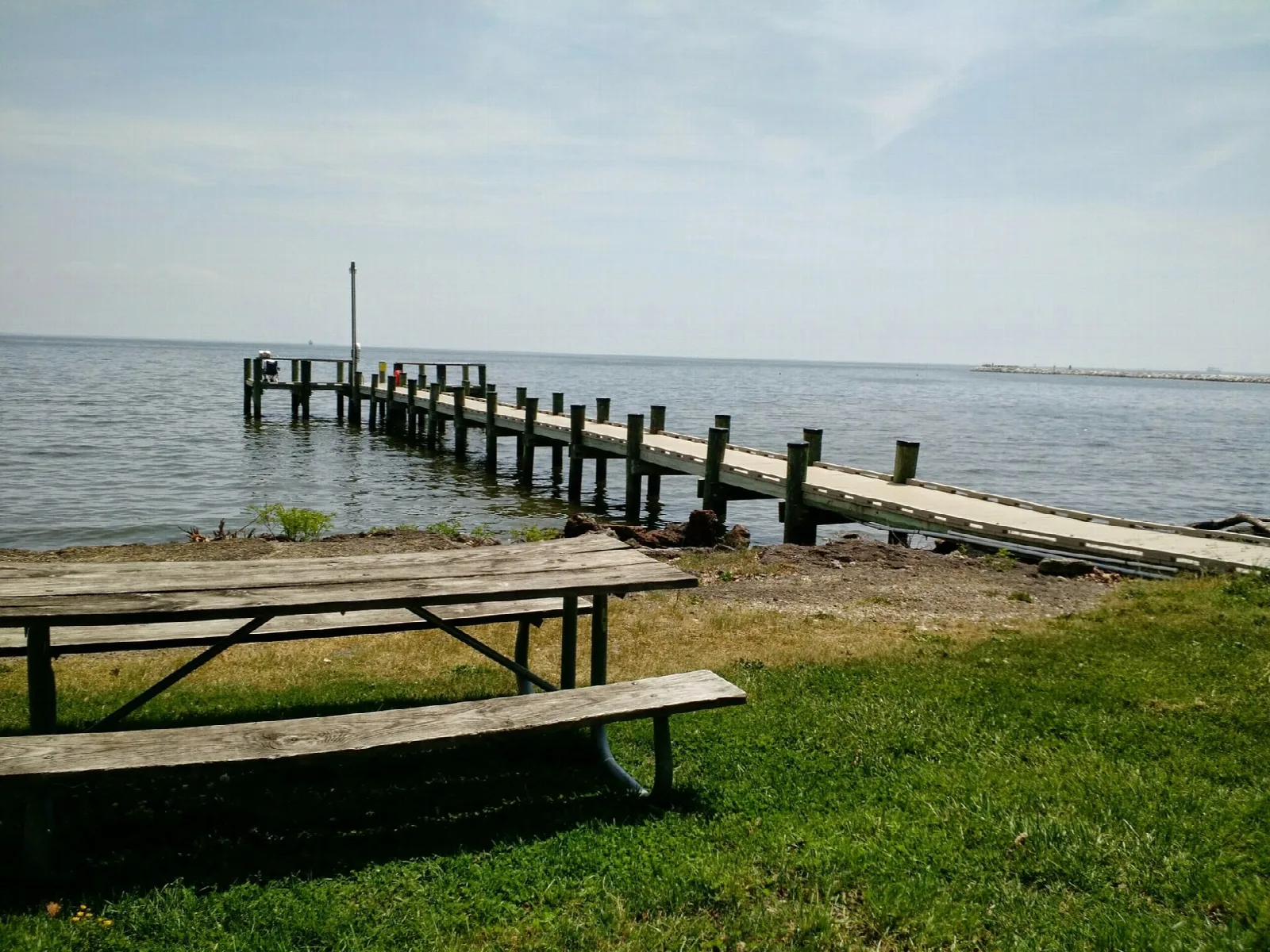 Wooden pier into the bay beside a picnic table on grass