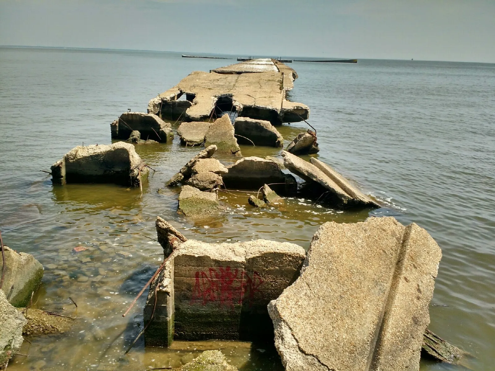 Large broken concrete blocks in shallow bay water