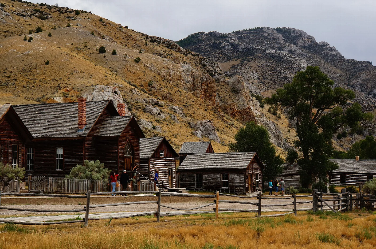 Log buildings along a fenced street with hills behind