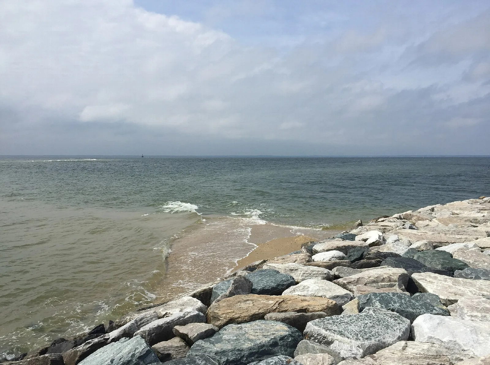 Rock jetty beside a sandy shore and open water