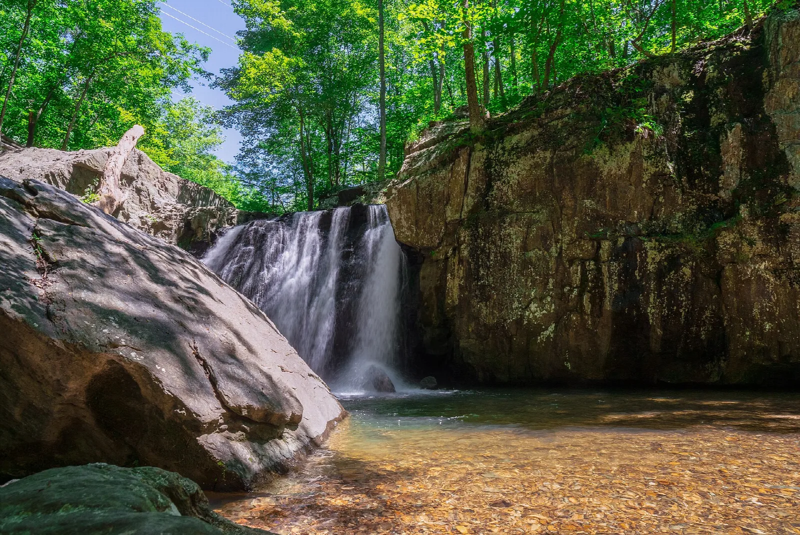 Kilgore Falls spilling over a rock ledge into a shallow pool, with green forest above