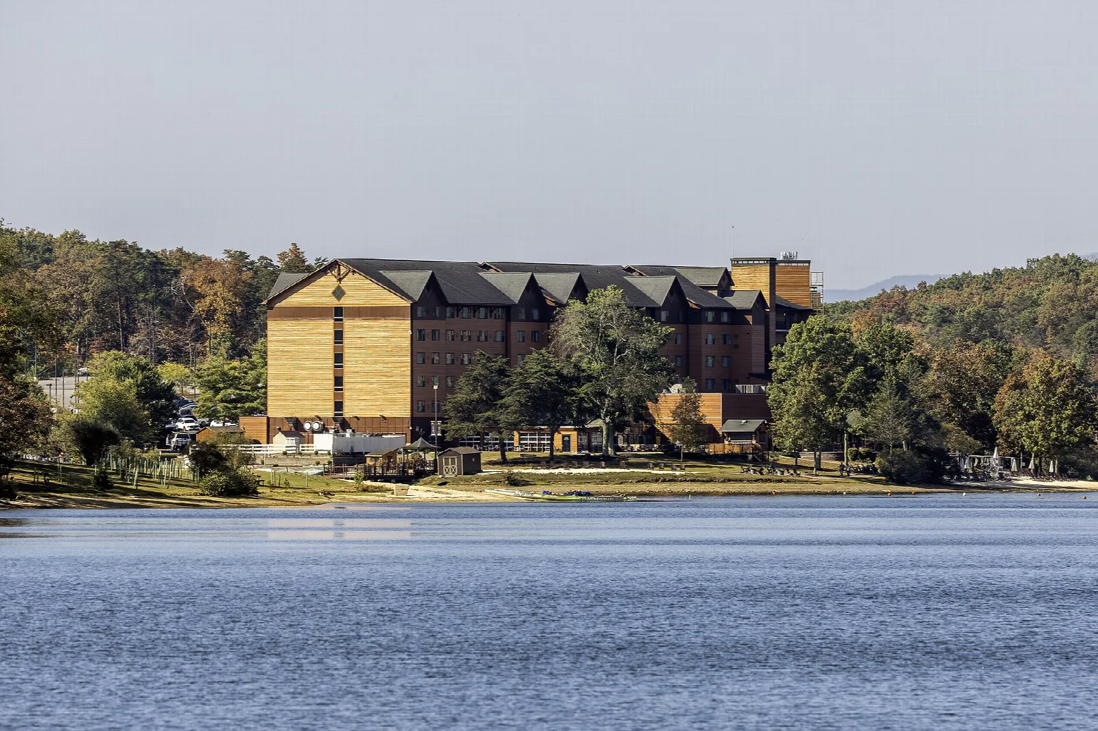 Large lodge building on a wooded shore across a lake