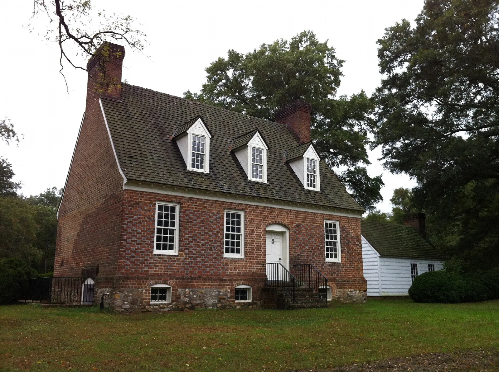Red brick colonial house with dormer windows on a lawn