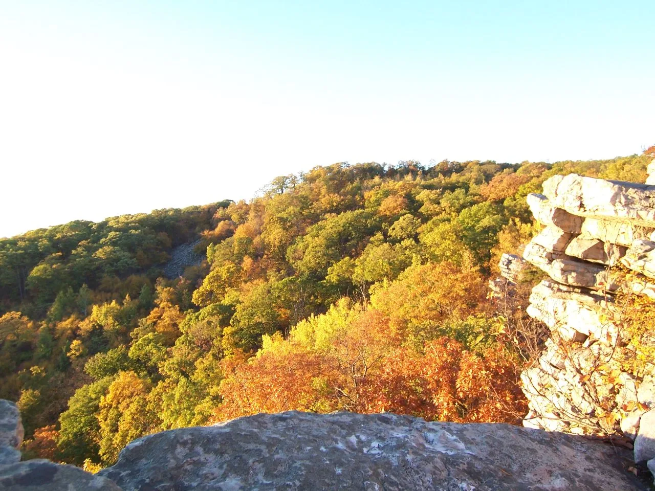 Rock outcrops over a valley of orange autumn trees