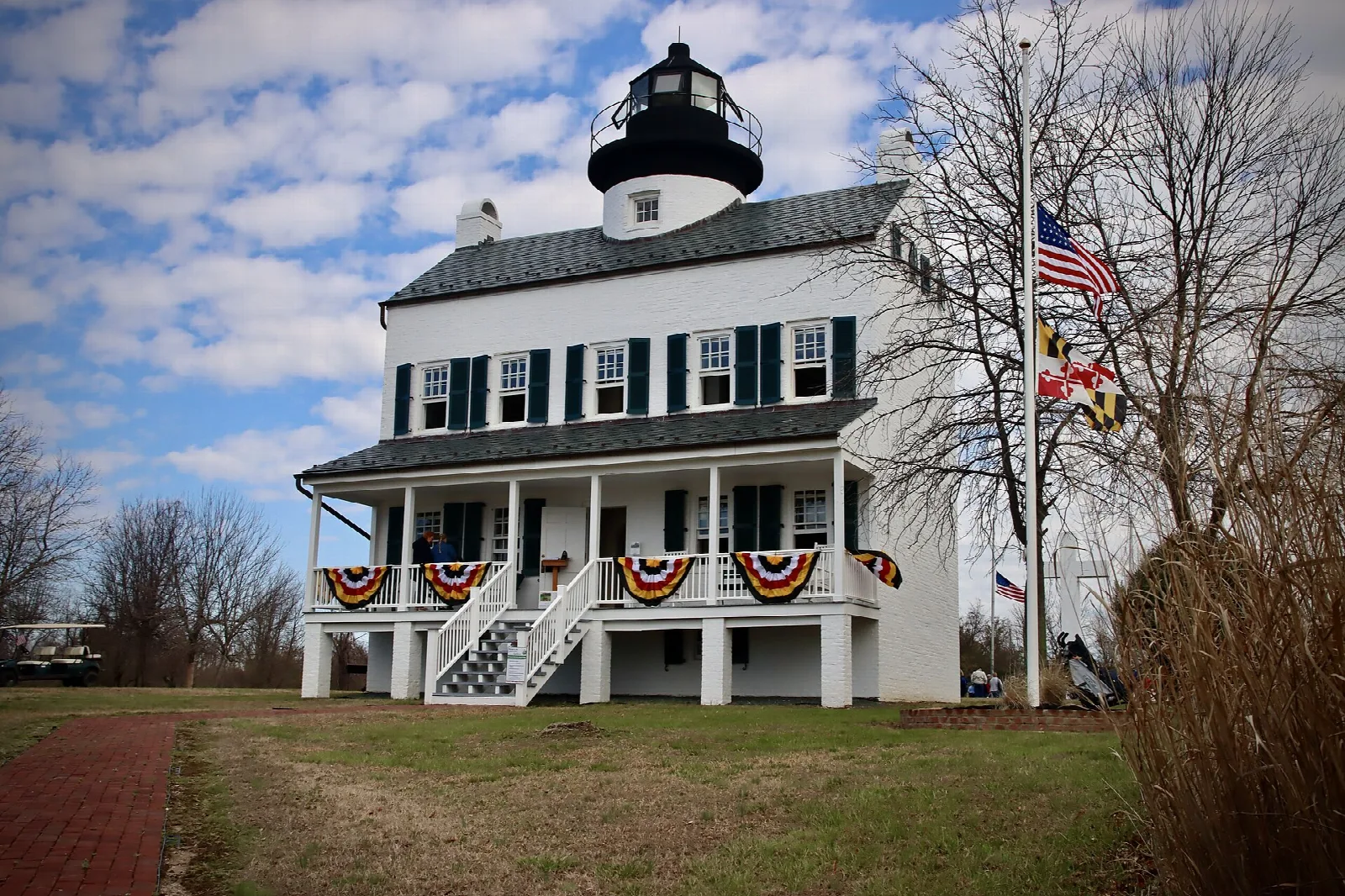 White lighthouse building with a black lantern room and flags