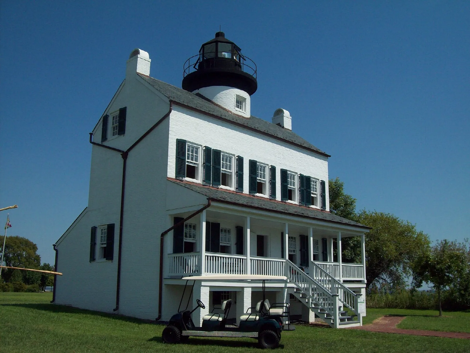 White lighthouse house with a porch and a cart on the lawn
