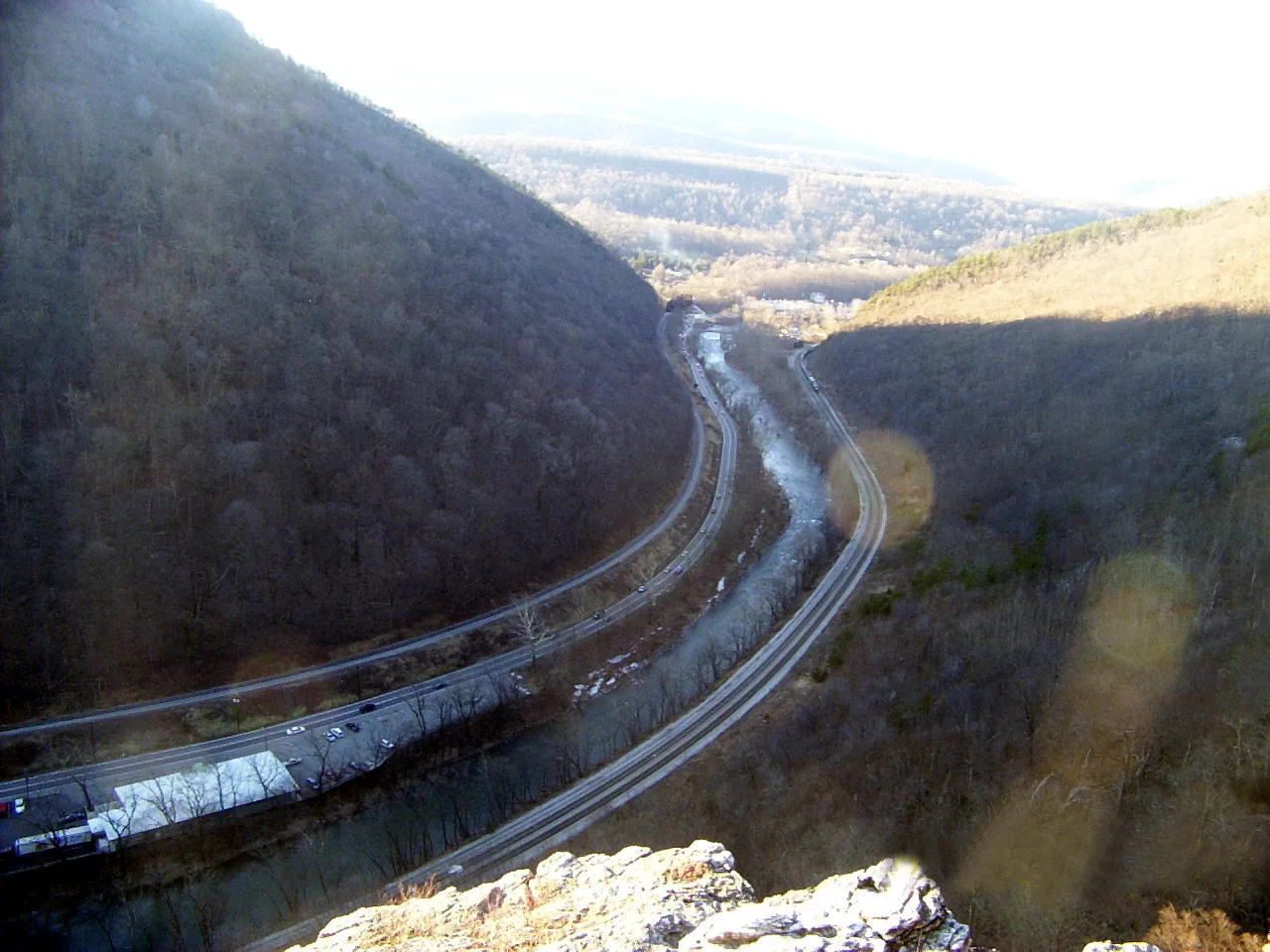 Road and river winding through a gap between steep wooded mountainsides