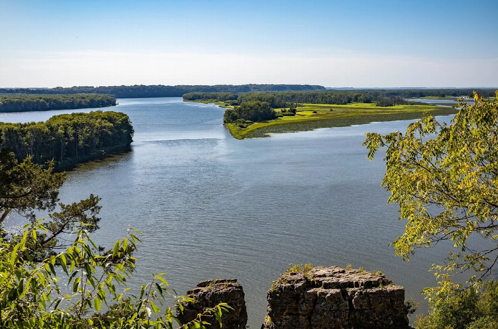 Wide river and wooded islands seen past rock outcrops