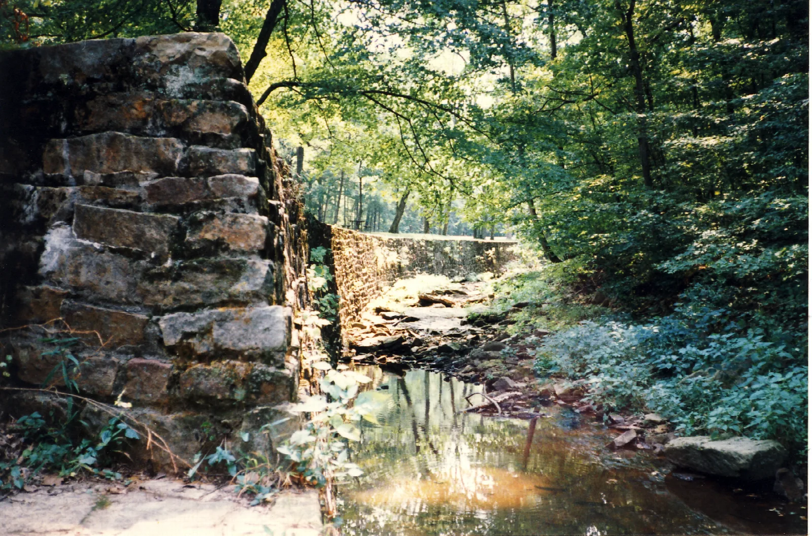 Old stone wall beside a shaded creek in the woods