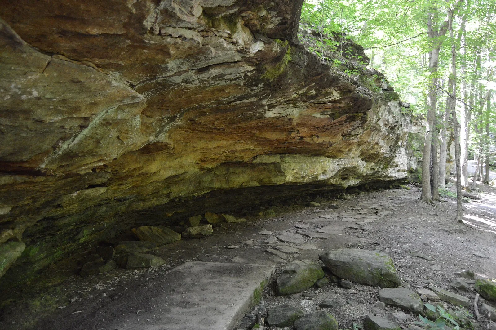 Sandstone rock shelter over a stone-lined trail in the woods