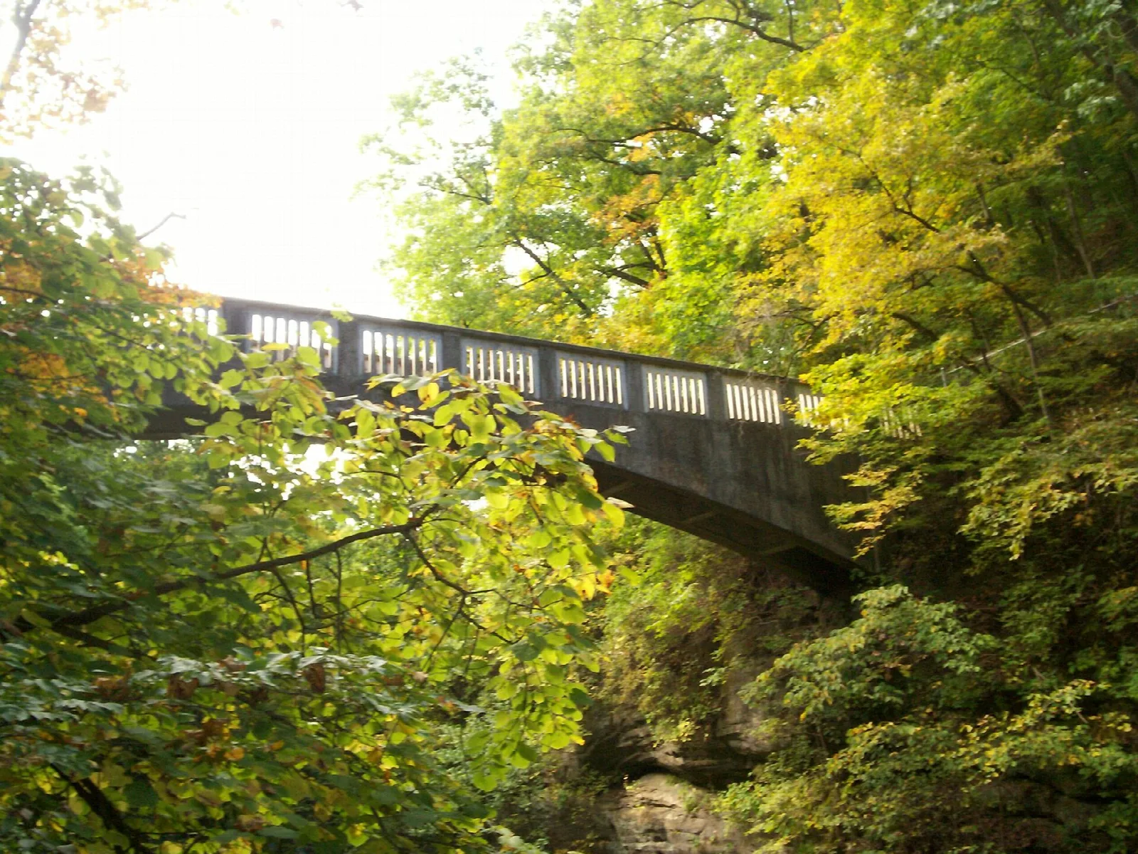 Stone bridge arching over a wooded ravine in autumn color