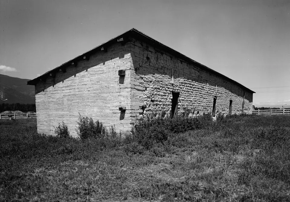 Black and white photo of an old adobe building in a field