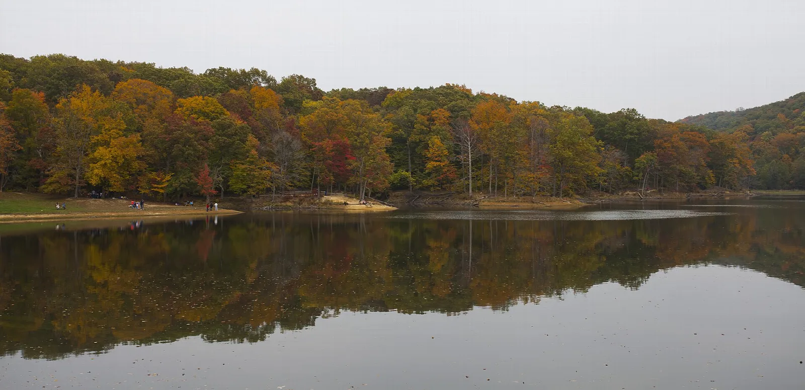 Still lake reflecting a shoreline of autumn trees