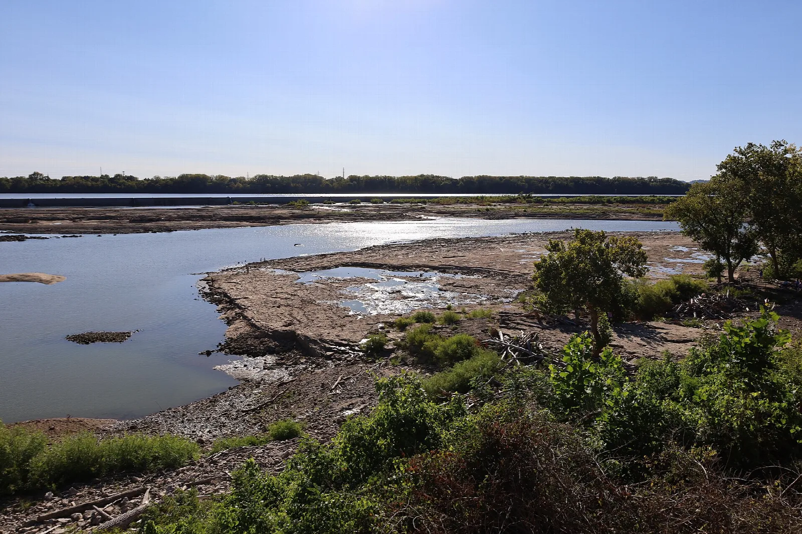 Rocky exposed river bed and a wide river under blue sky