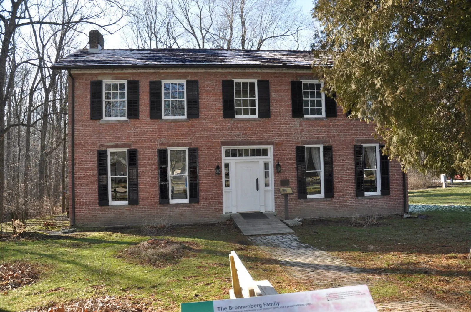 Two-story brick house with black shutters and a white door on a lawn