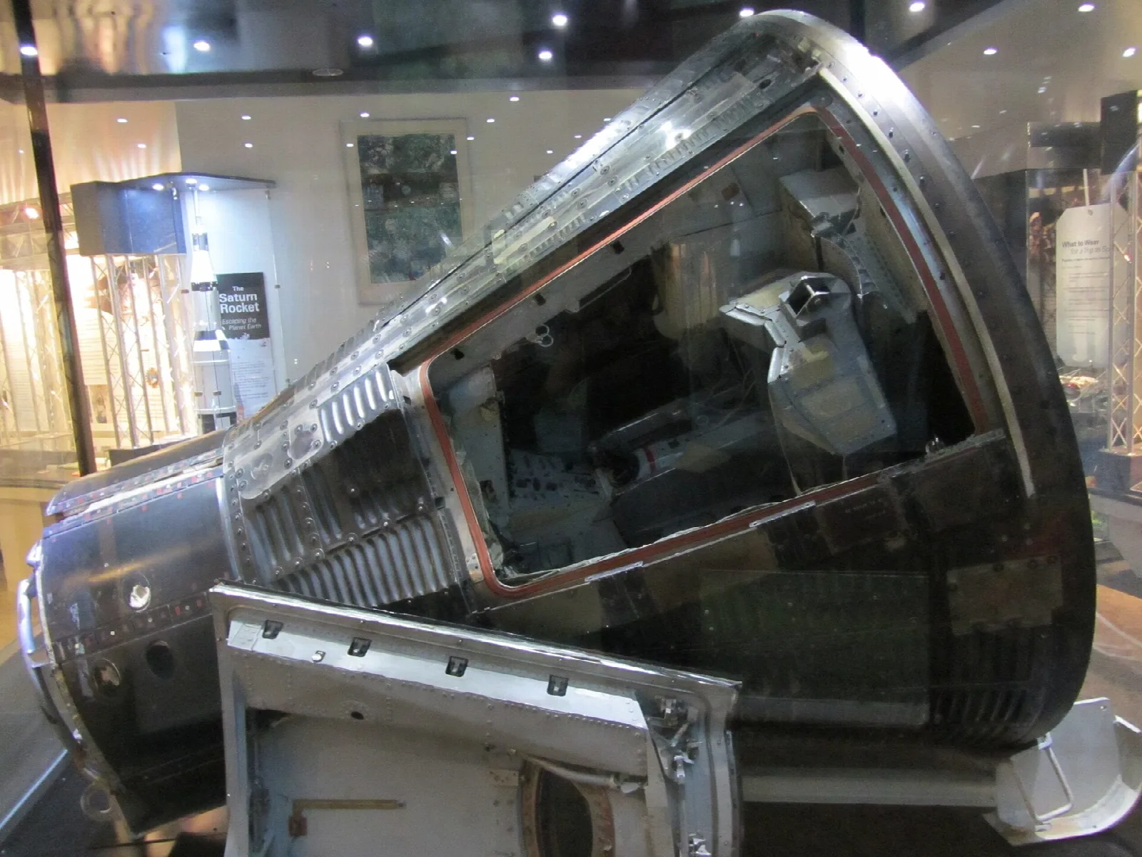 Dark metal Gemini space capsule on display in a museum room