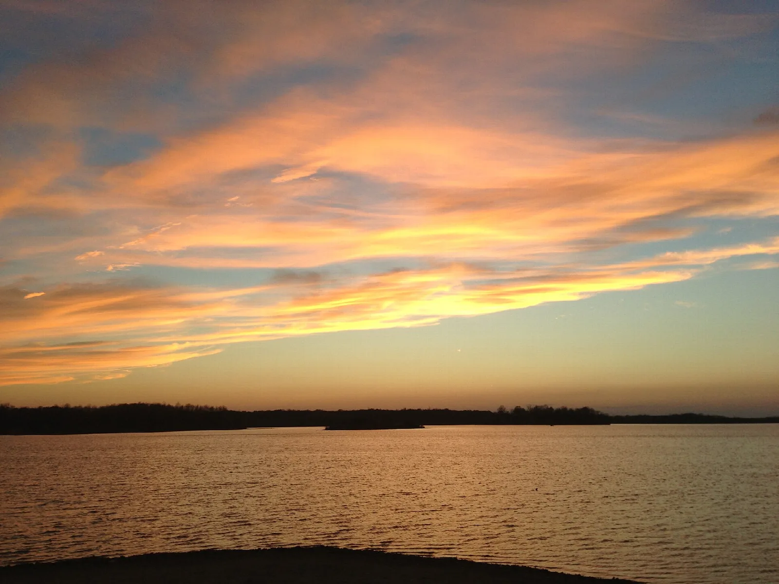 Orange and gold sunset clouds over a calm lake