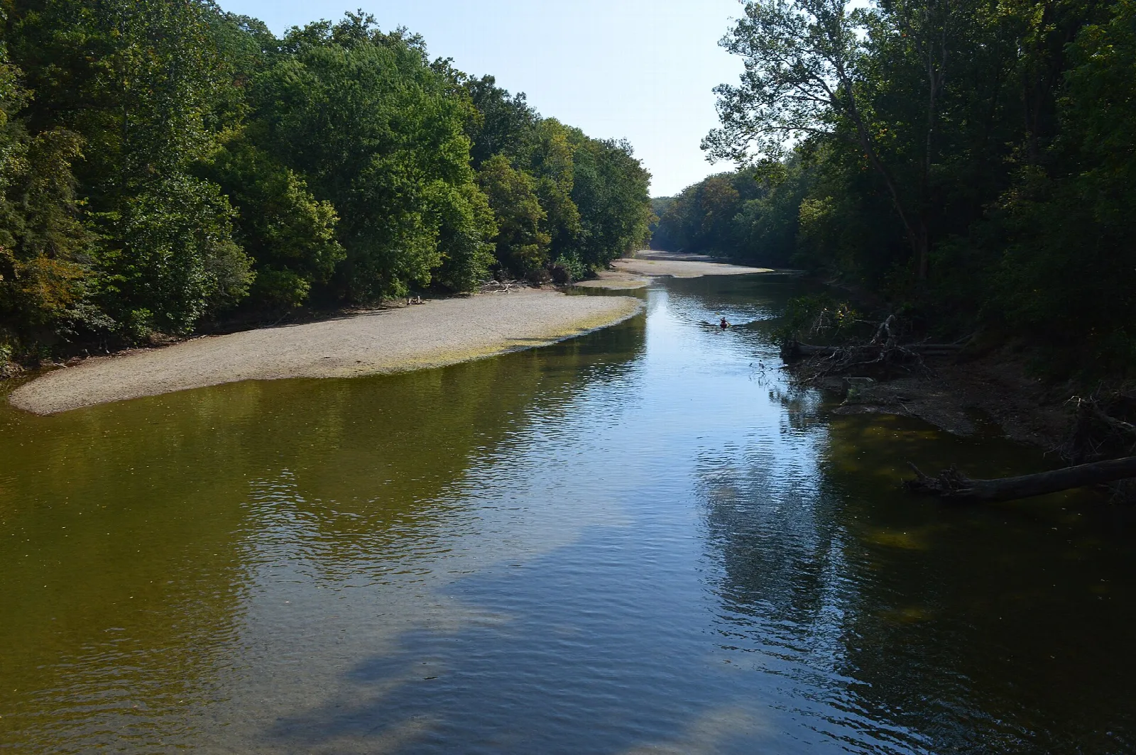 Calm river with a sandy bar and tree-lined banks