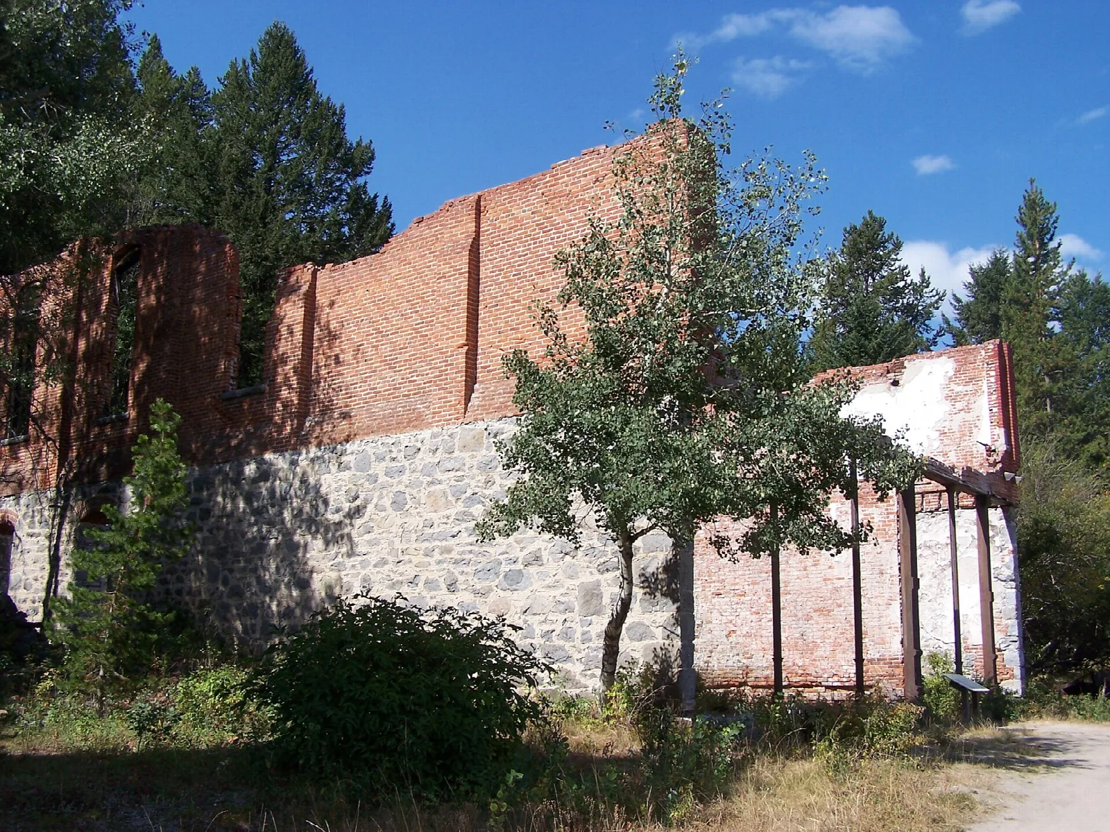 Ruined brick and stone walls of a large building among trees