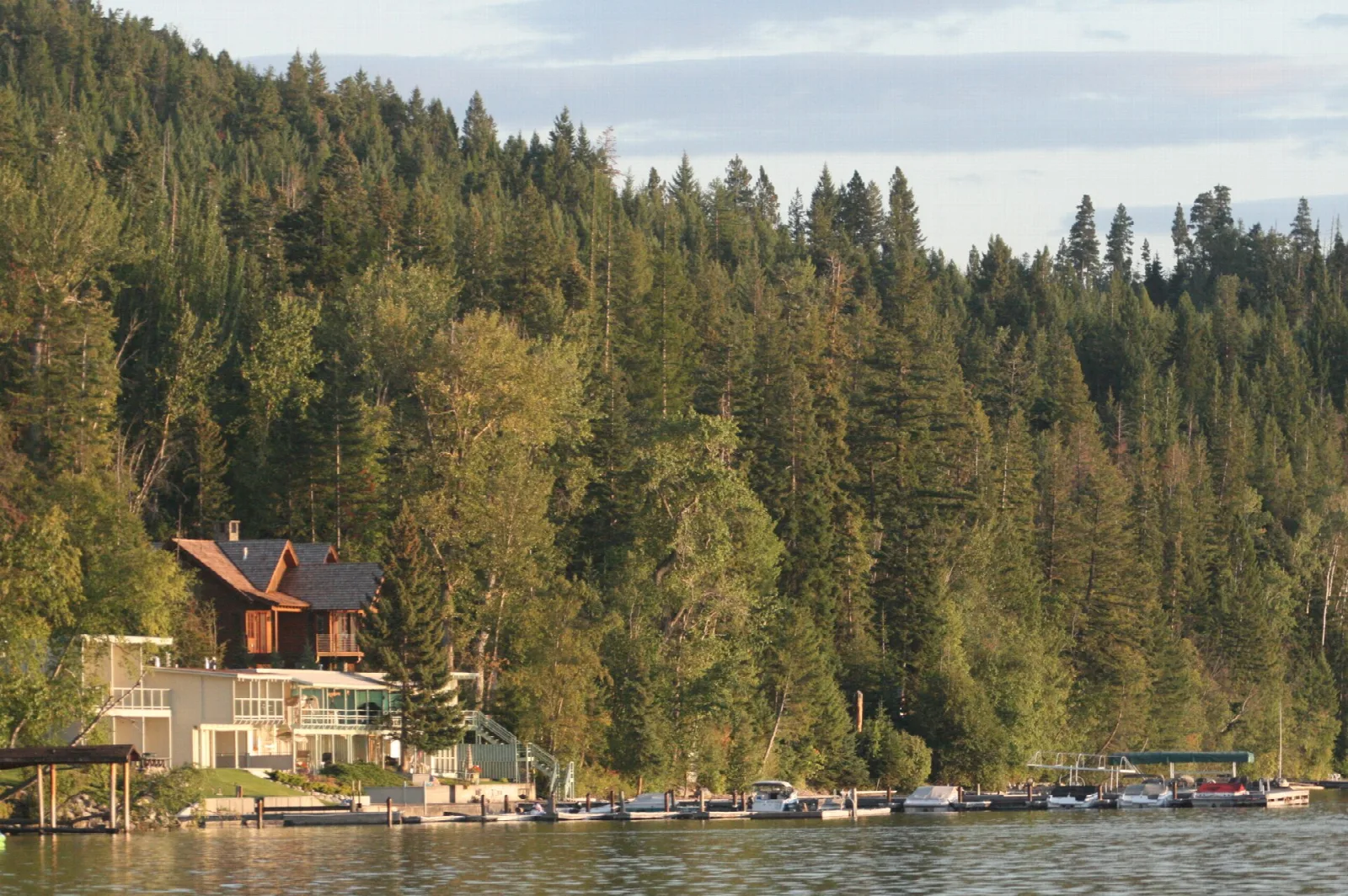 Forested shoreline on a lake with a lakeside house and boat docks