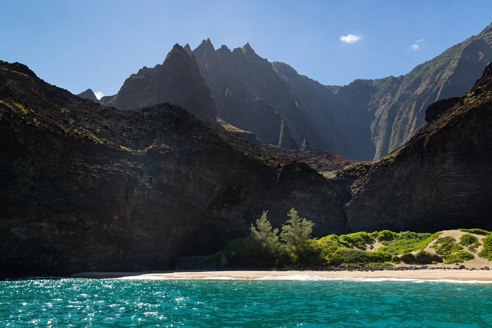 Jagged ridges rising behind a small beach with turquoise water in front