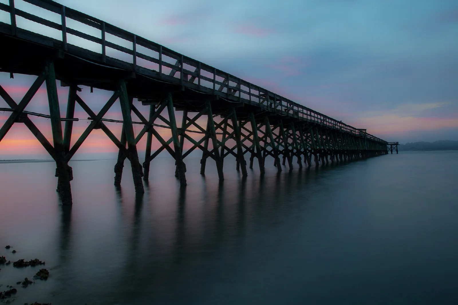 Long wooden pier stretching over calm water at dusk