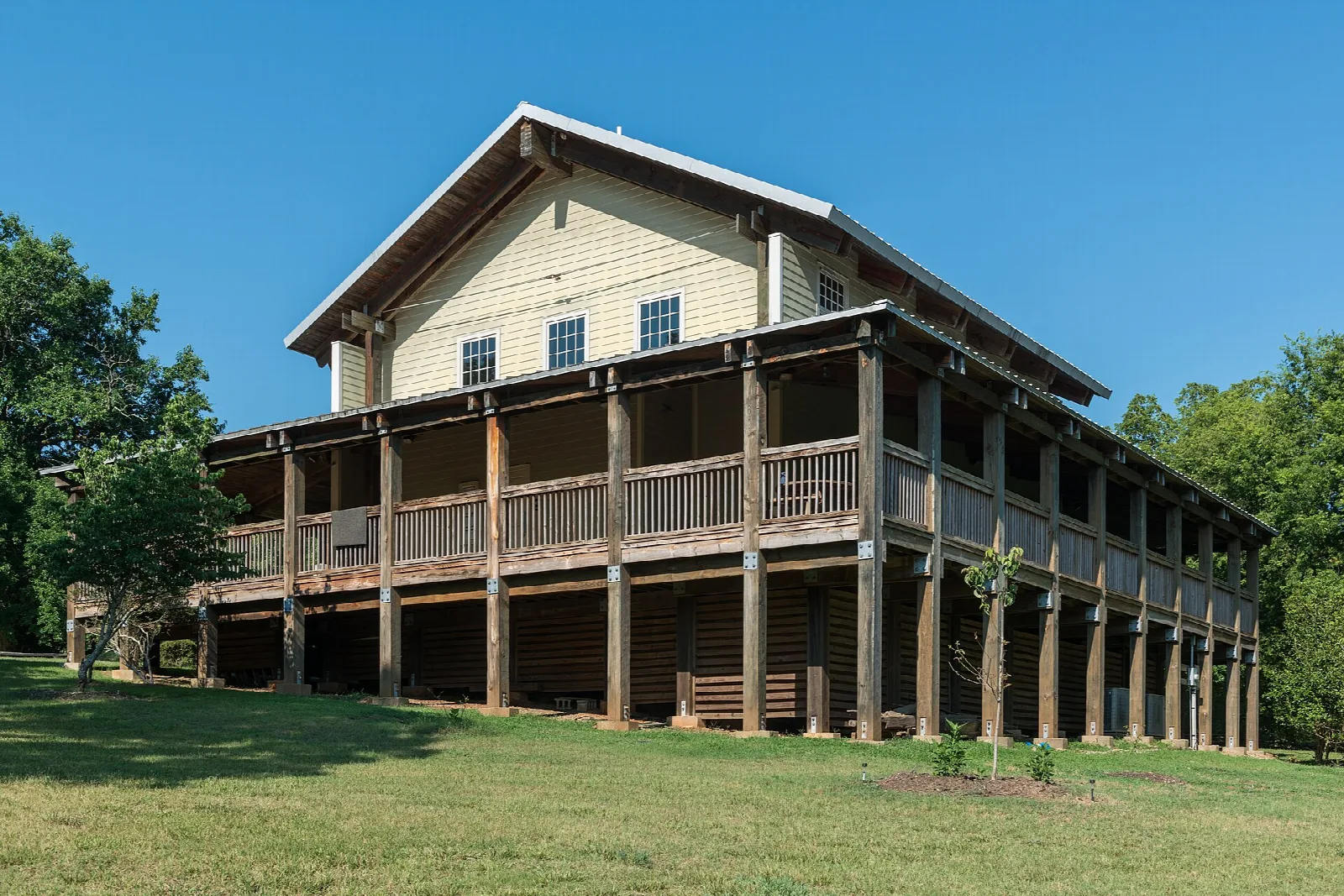 Wooden visitor center with a wide wraparound porch beside a lawn