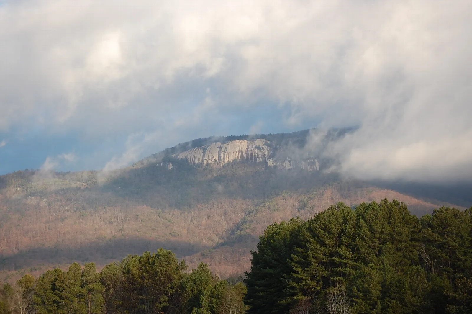 Table Rock Mountain's bare granite face rising above clouds and forested ridges