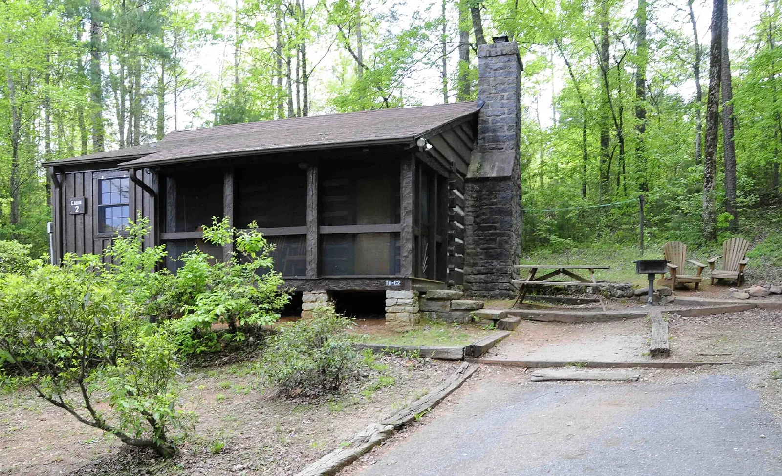 Dark log cabin with a stone chimney in the woods