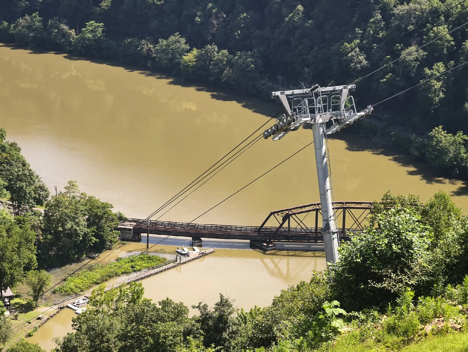 Aerial tram tower above a river and a rail bridge