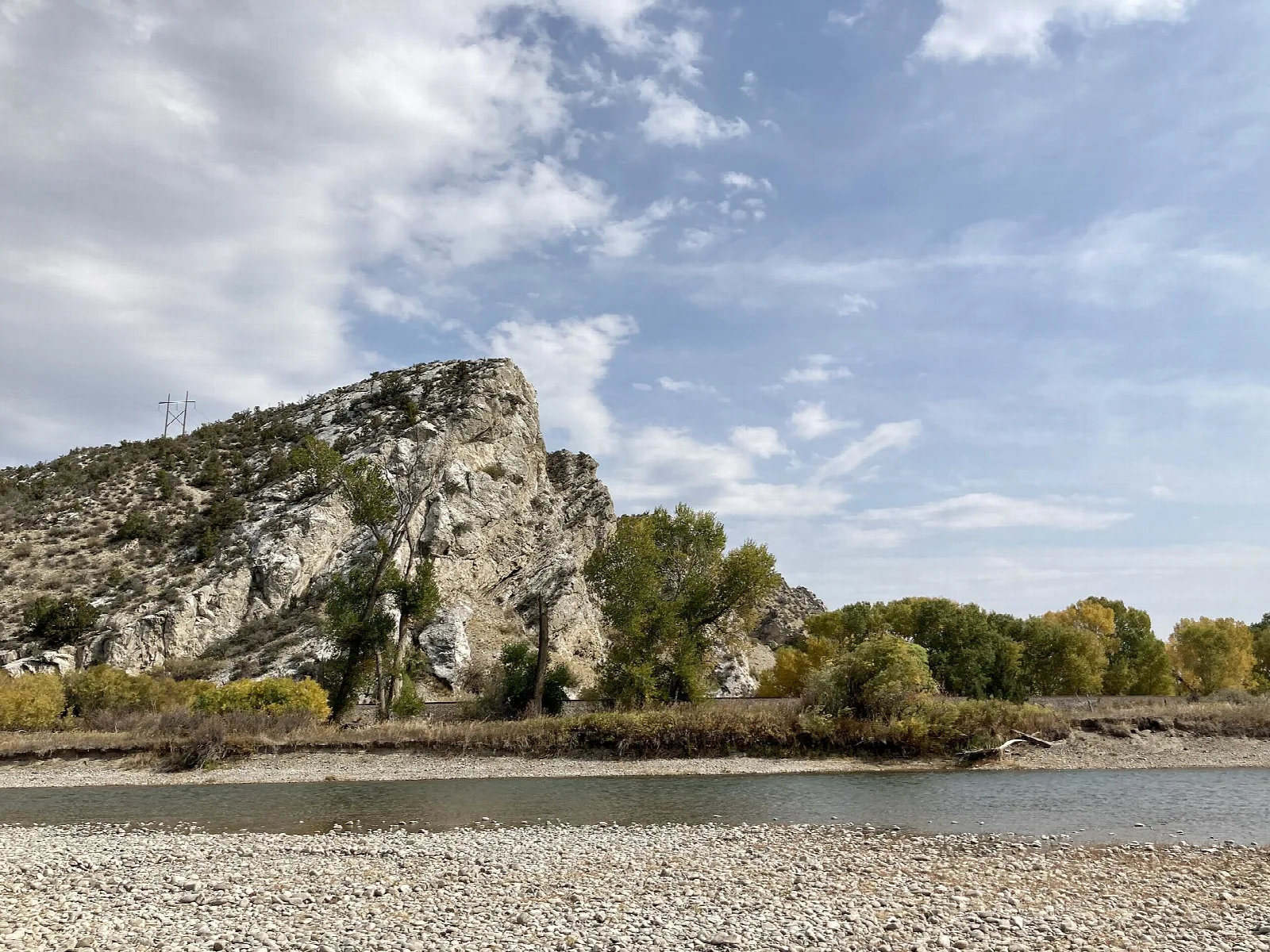 Rocky bluff rising above a gravel bar and river
