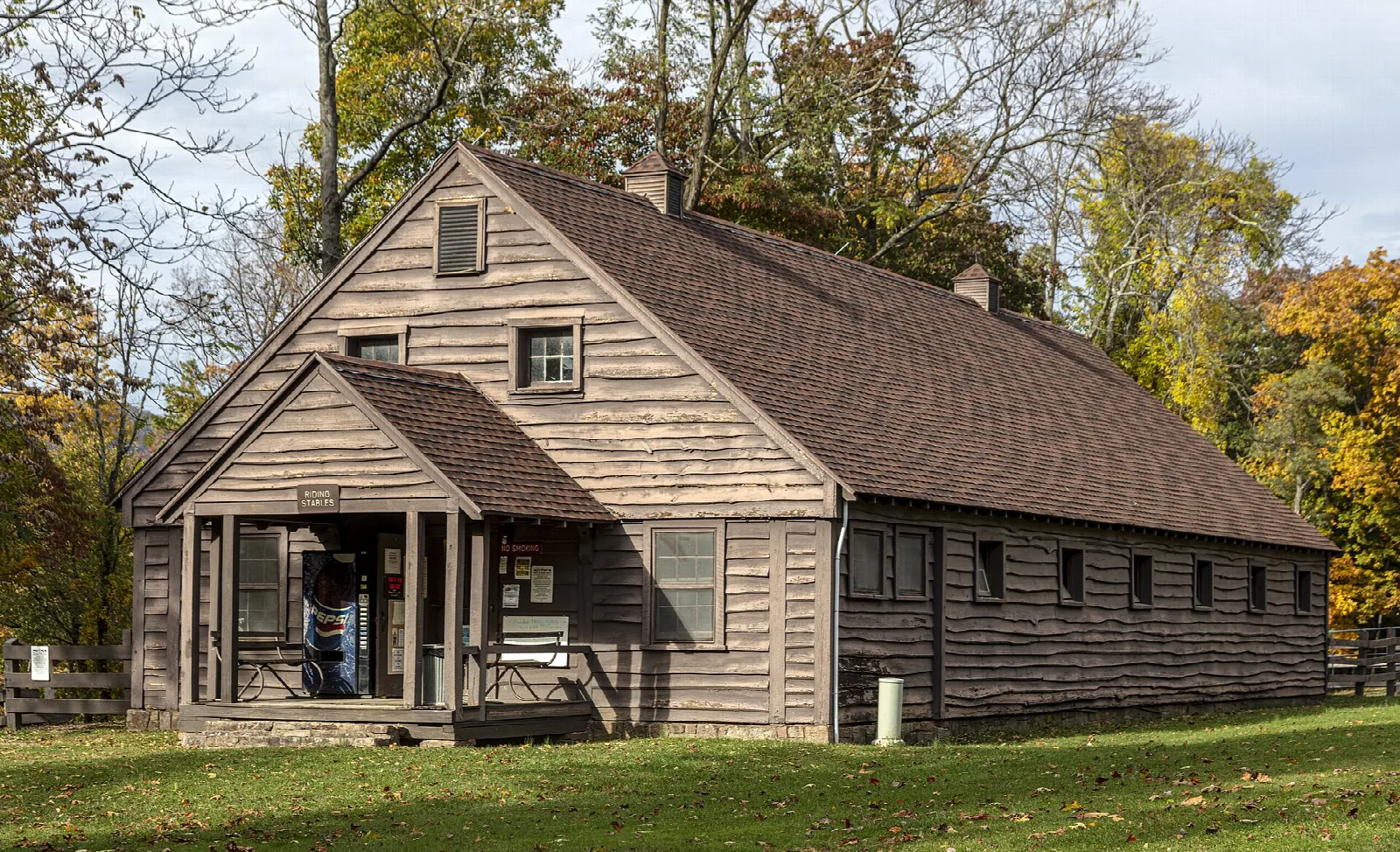 Wooden riding stable building among fall trees