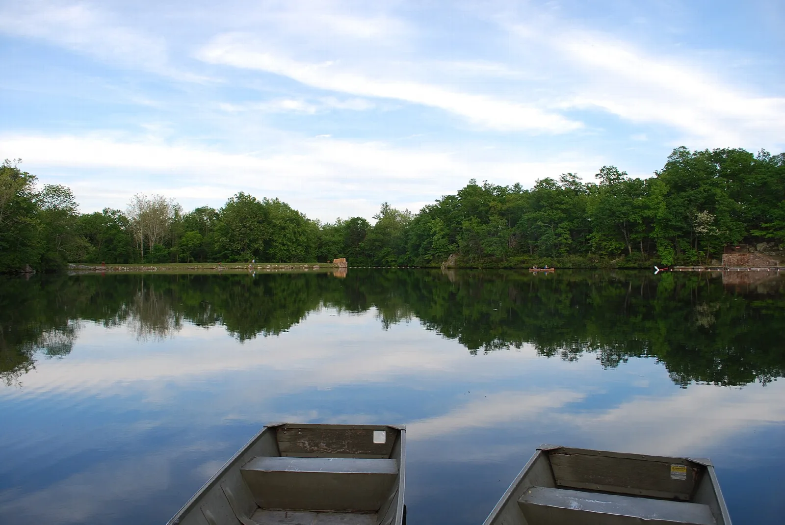 Calm lake with two rowboats and wooded shore