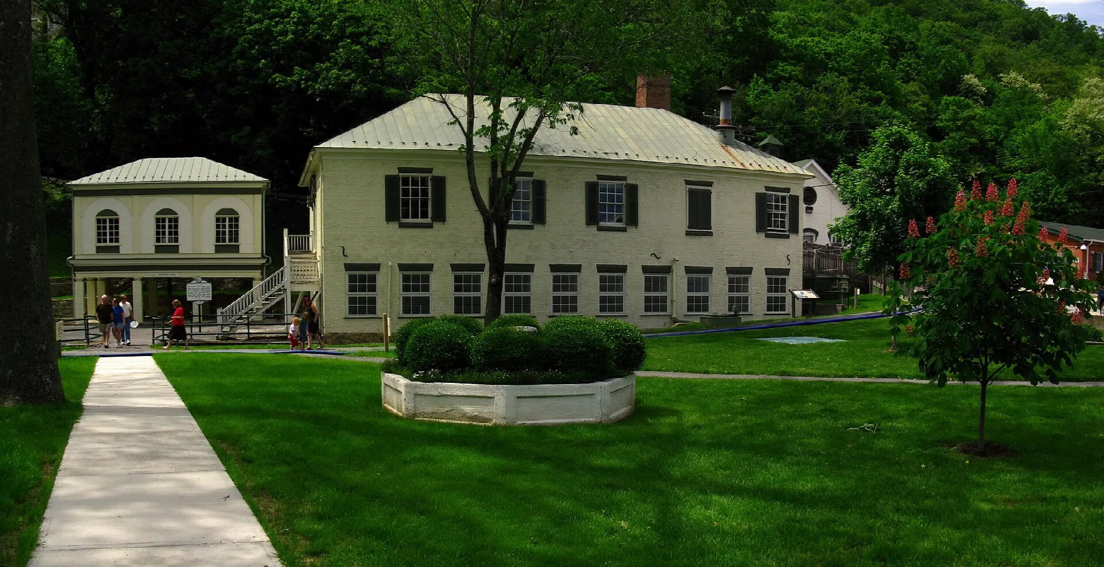 Historic spa buildings on a green lawn with trees behind