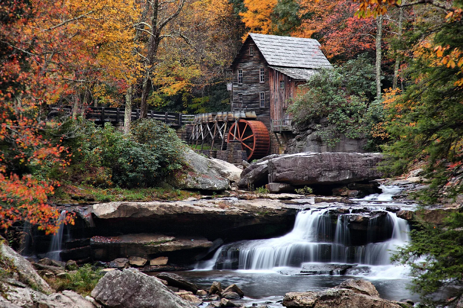 Grist mill above a waterfall among orange autumn trees