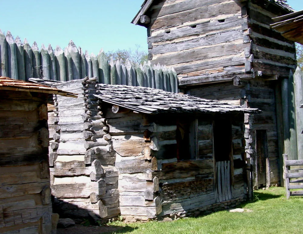 Log buildings and a tall wooden palisade of the fort