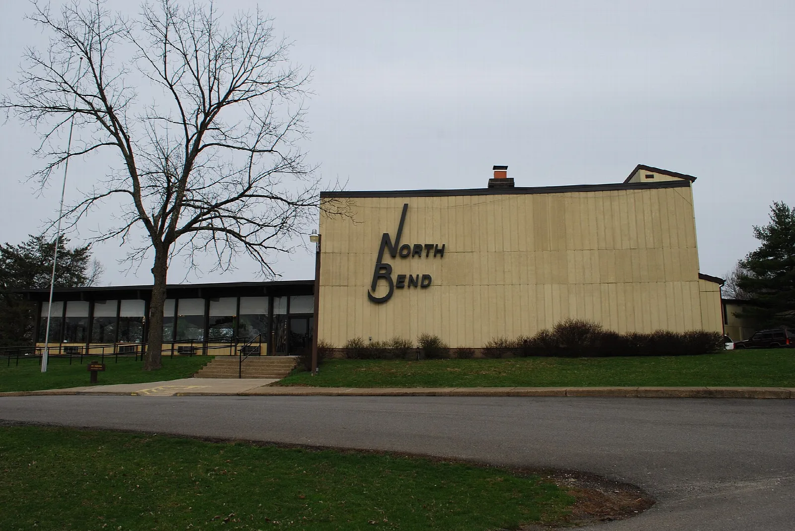 Tan lodge building with a North Bend sign beside a curving road