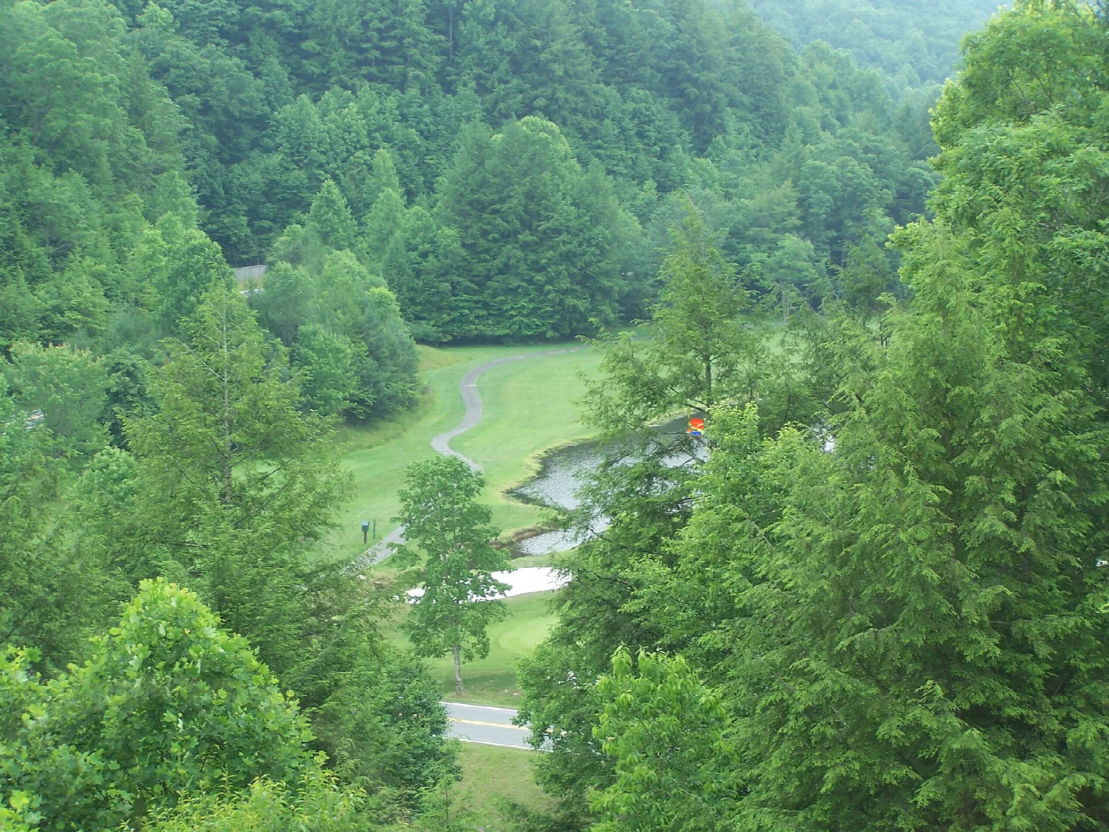 Green forested hills with a golf course fairway winding through the valley
