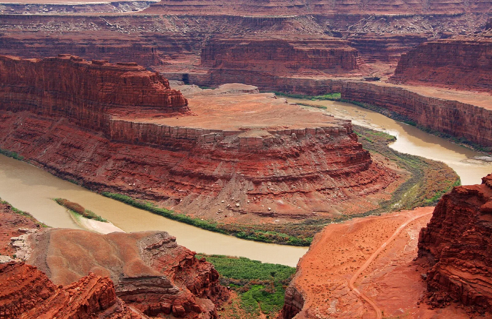 Colorado River curving around a rust-colored rock bench far below