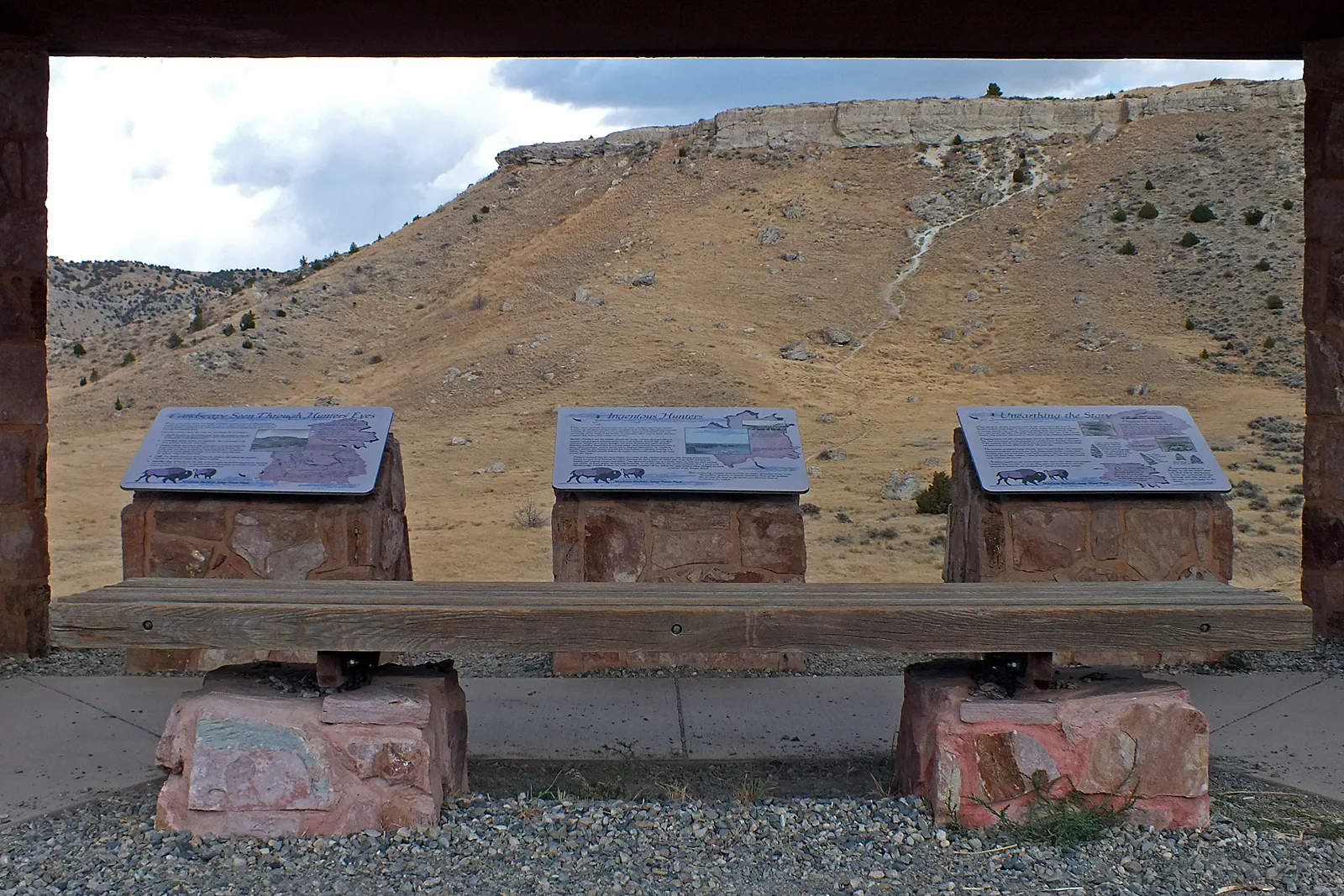 View through a wooden shelter of the cliff with three interpretive panels