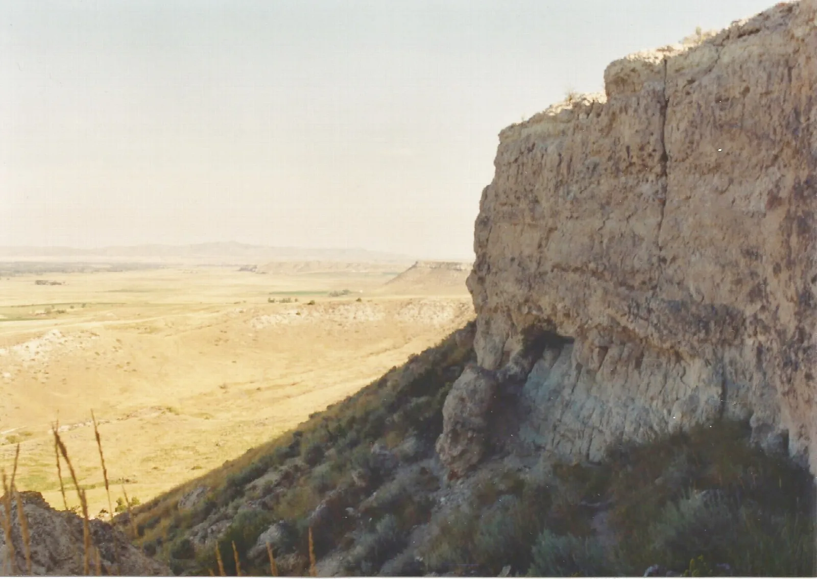 Tall pale limestone cliff face above a wide open valley