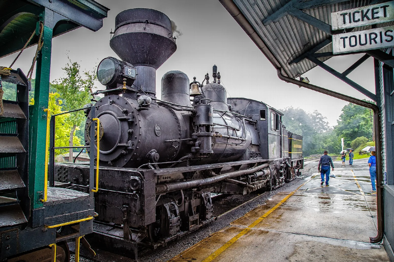 Black steam locomotive waiting at the station platform under a roof