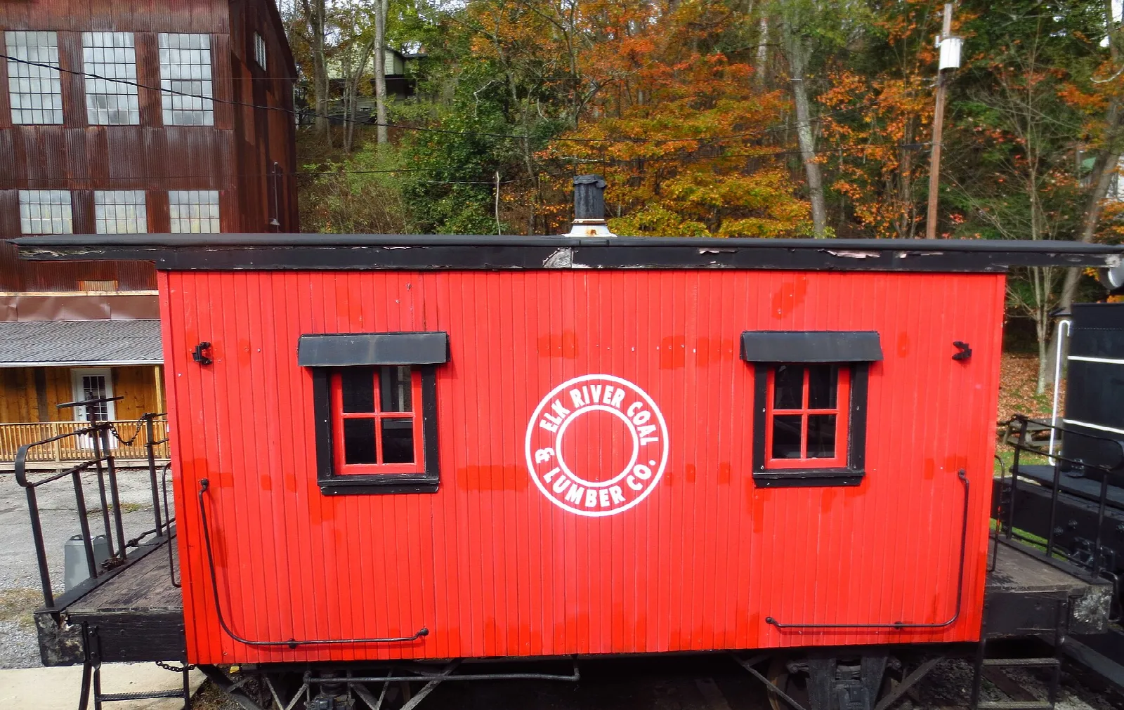 Red caboose with small windows beside a brick building